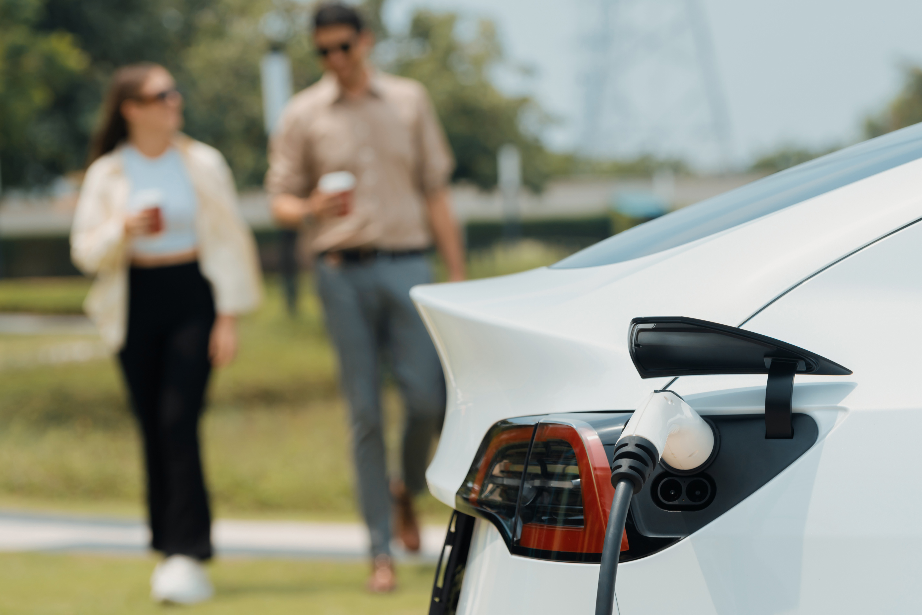 Young couple put EV charger to recharge electric car battery. Expedient